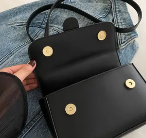 Close-up of black leather bag featuring double golden hardware magnetic buckles for closure