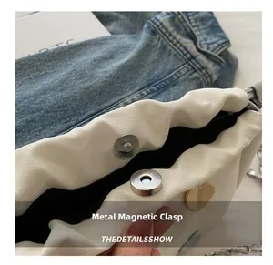 Gros plan du fermoir magnétique argenté sur le sac à main en cuir grainé blanc