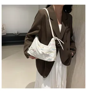 Gros plan d'un sac cabas blanc matelassé avec broderie vagues colorées et nœud sur mannequin