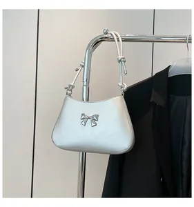 Détail de l'ornement nœud argenté et de la bandoulière nouée sur le sac à main