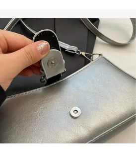 Close-up of silver textured handbag with metallic finish and magnetic snap closure