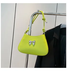 Détail du sac bandoulière vert fluo avec nœud en métal argenté et bandoulière nouée