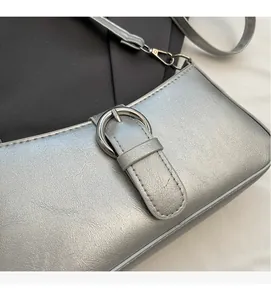Close-up of silver crossbody bag with metallic texture and round buckle detail