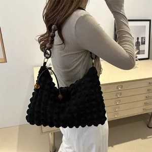 Sac à bandoulière en seersucker noir avec sangle en perles de bois porté par un mannequin