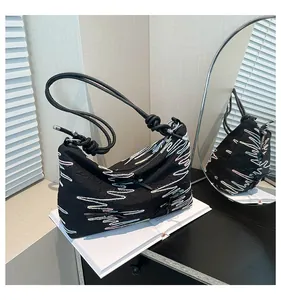 Détail du sac en nylon noir avec broderie zigzag colorée et poignées décoratives à nœuds