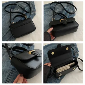 Interior detail of black leather crossbody bag showing internal space and golden buckle