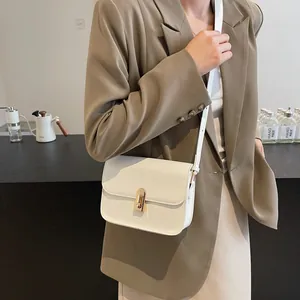 Petit sac à bandoulière blanc crème minimaliste avec boucle dorée en scène lifestyle