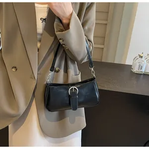 Detail of a minimalist black baguette shoulder bag with a silver metal buckle