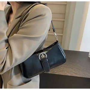 Close-up of black baguette shoulder bag with silver buckle worn with a khaki blazer