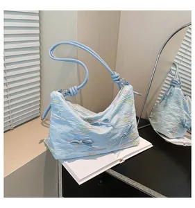 Détail du sac cabas bleu clair avec broderie ondulée colorée et décoration de nœud en 3D