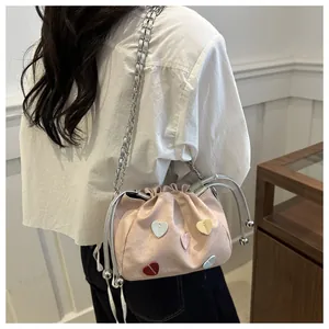 Modèle portant un sac seau rose aux cœurs colorés avec une bandoulière en chaîne