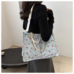Detail of light blue tote bag with cherry prints and adjustable canvas straps
