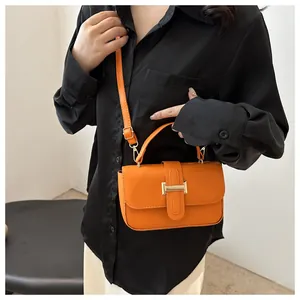 Model wearing a bright orange faux leather crossbody bag with a gold buckle and shoulder strap