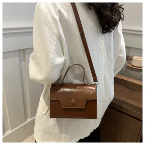 Sac bandoulière vintage en cuir PU marron porté sur un costume blanc par un mannequin