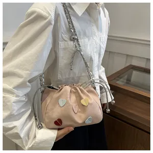 Détail du sac seau rose en daim avec patchs en forme de cœur et bandoulière chaîne