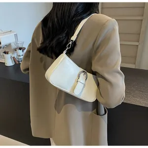 Detailed close-up of cream faux leather crossbody bag with a large metallic buckle