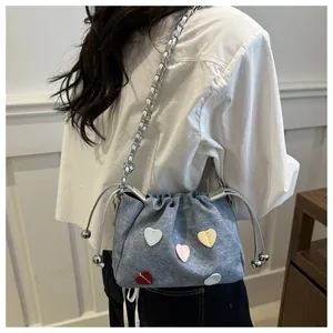 Détail d'un sac seau gris avec appliques cœur colorées et bandoulière chaîne