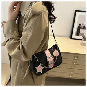 Detalle de bolso vaquero de hombro con estrellas de cuero rosa y correa de cadena de metal plata