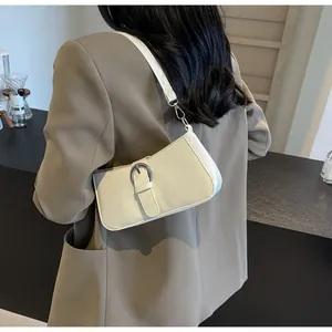Detail of minimalist cream white shoulder bag with silver buckle worn on a brown blazer