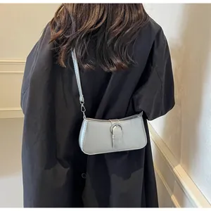 Chic silver crossbody bag with metal ring detail worn over a black trench coat
