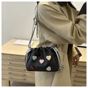 Détail du sac seau noir à cordon avec cœurs en cuir colorés et bandoulière chaîne