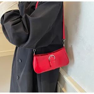 Detailed shot of a red minimalist underarm bag featuring a silver circular metal buckle