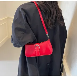 Detailed view of red leather underarm bag featuring a large silver round metal buckle