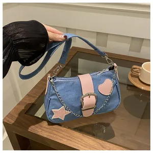 Détail du sac croissant en denim avec patchs d'étoiles roses et chaîne sur une table
