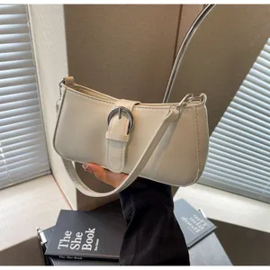 Detail of cream white faux leather underarm bag featuring a silver metal buckle and strap