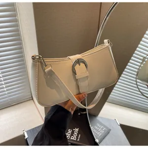 Detail of cream white leather underarm bag featuring a silver metal buckle accent