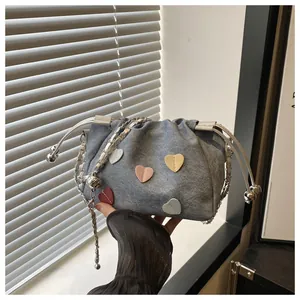 Vue détaillée du sac seau en denim gris avec patchs cœurs colorés et bandoulière chaîne