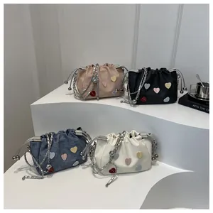 Détail des sacs seaux à motifs de cœur en rose, noir, bleu et blanc avec chaîne