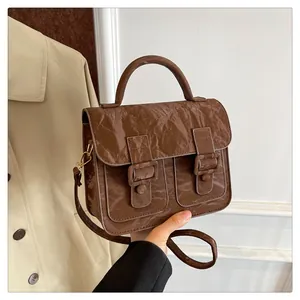 Detail einer braunen Vintage-Tasche mit Knitter-Lackleder-Effekt und zwei Schnallenriemen