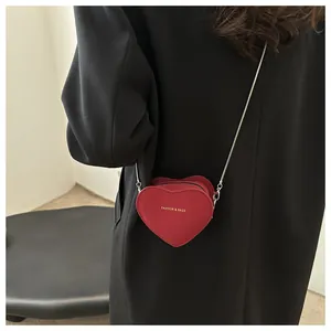 Détail du mini sac bandoulière rouge en forme de cœur avec lettrage doré et chaîne argent
