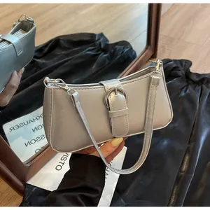 Close-up of a silver metallic shoulder bag featuring a bold round buckle and wide strap