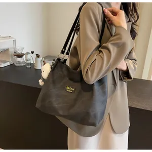 Detail view of black matte tote bag with yellow label and cute white plush bear pendant