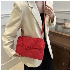 Détail du sac à bandoulière matelassé rouge avec chaîne en résine et tissu en nylon