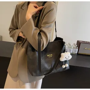 Detail view of large black matte tote bag with plush charm on a fashion model
