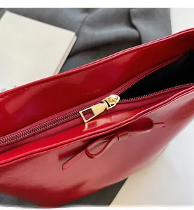 Detail of red glossy bucket bag featuring smooth metal zipper and decorative bow