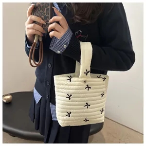 Detailed view of a white quilted bucket handbag with black floral embroidery on model