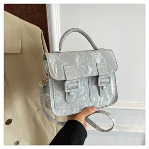 Nahaufnahme einer silbernen Cambridge-Tasche mit Knitteroptik, Tragegriff und Schultergurt
