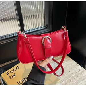 Close-up of bright red patent leather handbag featuring a stylish silver metal buckle detail