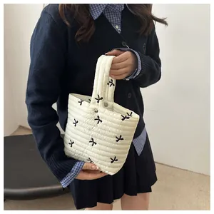Detailed shot of white quilted mini handbag with black bow embroidery and magnetic closure