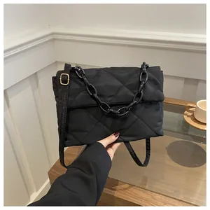 Détail d'un sac bandoulière noir matelassé avec chaîne acrylique et boucle dorée réglable