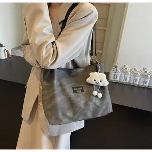 Close-up of a charcoal grey canvas tote bag with MiaTmait label and plush cloud charm