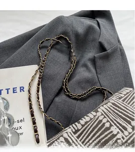 Close-up of woven shoulder bag featuring gold chain strap with leather detail