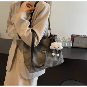 Model wearing dark grey vintage canvas tote bag with cloud plush charm detail