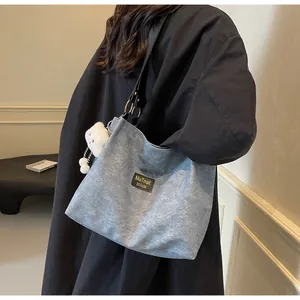Close-up of light blue tote bag with black leather straps and a white plush bear charm