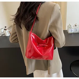 Detail showing the glossy red patent leather finish and delicate bow on the bucket bag