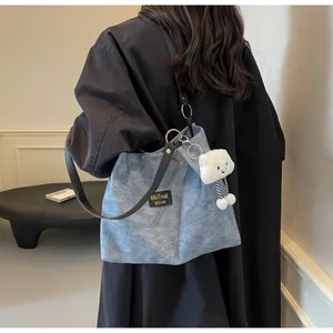 Blue denim tote bag with black leather straps and white plush cloud charm detail